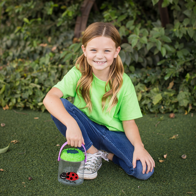 Girl in green shirt kneeling holding a Best Ever Bug Jar
