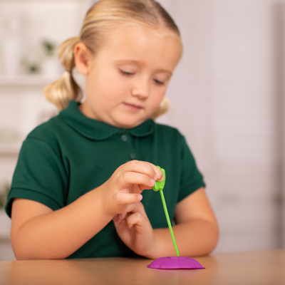 Child using green nectar dropper to place nectar on purple butterfly feeder