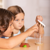 Two Children looking a chrysalides on a Cup of Caterpillars lid