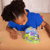 Small girl with blue shirt looking into green, blue, and purple Ladybug Land